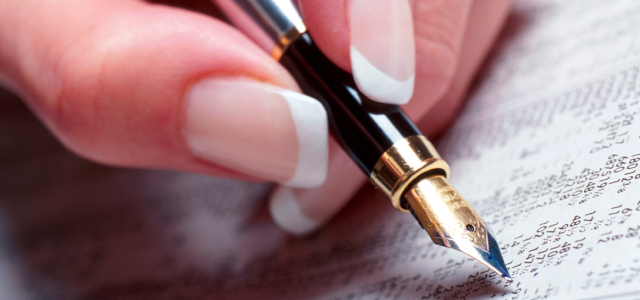 A woman's hand holding a fountain pen over a list