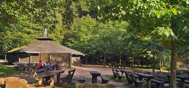 Einige feste Sitzplätze sind im Freien. Die Hütte selbst ist aus Holz und nicht ganz geschlossen, dafür aber überdacht.