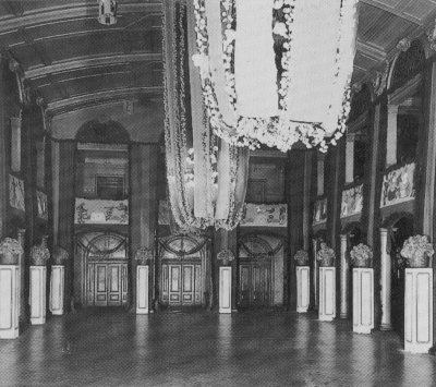 Der große Saal ist mit tief hängenden Kronleuchtern festlich geschmückt. An den Balkonen sind individuelle Szenen aus Kunst, Theater und Musik aufgemalt.