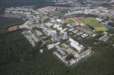 Eine Luftaufnahme auf der die vom Pfälzer Wald umgebene Uni zu sehen ist. Weiter hinten liegen die Forschungseinrichtungen und die Uni-Wohnstadt.