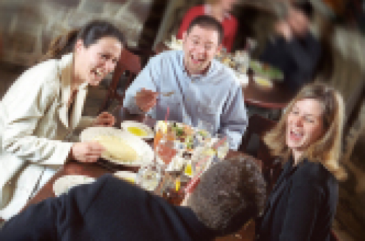 Blick auf zwei Paare in ausgelassener Stimmung beim gemeinsamen Essen in einem Restaurant.  