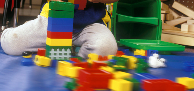 Einen Blick auf einen kleinen Jungen im Kindergarten der mit bunten Spielbausteinen spielt