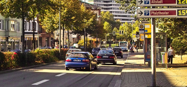 Man blickt die Rudolf-Breitscheid-Straße hinunter in Richtung Rathaus. Mehrere Autos und ein Bus fahren auf dieser Straße über eine grüne Ampel. Direkt vor dem Betrachter steht eine Bushaltestelle.