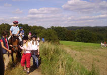 Foto zeigt eine Gruppe Mädchen zu Fuß und hoch zu Ross auf freiem Feld