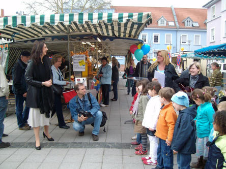 Foto zeigt Bürgermeisterin Dr. Susanne Wimmer-Leonhardt (links im Bild) und Kinder des Kinderhort Hokuspokus auf dem Donnerstagsmarkt