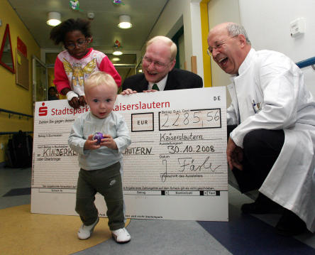 oto zeigt rechts im Bild Professor Dr. Gerhard Rupprath, links Beigeordneter Joachim Färber mit kleinen Patienten der Kinderklinik bei der Scheckübergabe