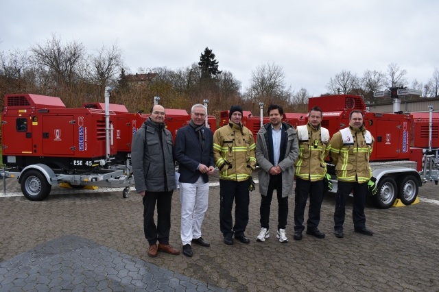 Gruppenbild der Verantwortlichen um Feuerwehrdezernent Steinbrenner vor den Notstromaggregaten. © Stadt Kaiserslautern