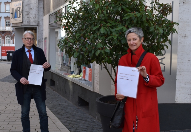 Auf dem Bild sind Bürgermeisterin Beate Kimmel und Oberbürgermeister Klaus Weichel mit dem Förderprogramm in der Innenstadt zu sehen. © Stadt Kaiserslautern