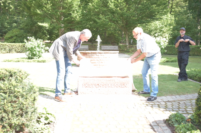 Beigeordneter Peter Kiefer und Wettbewerbsteilnehmer Bernhard Opp bei der Taufe des Friedensbrunnens. Rechts im Hintergrund: Steinmetz Harald Deege © Stadt Kaiserslautern