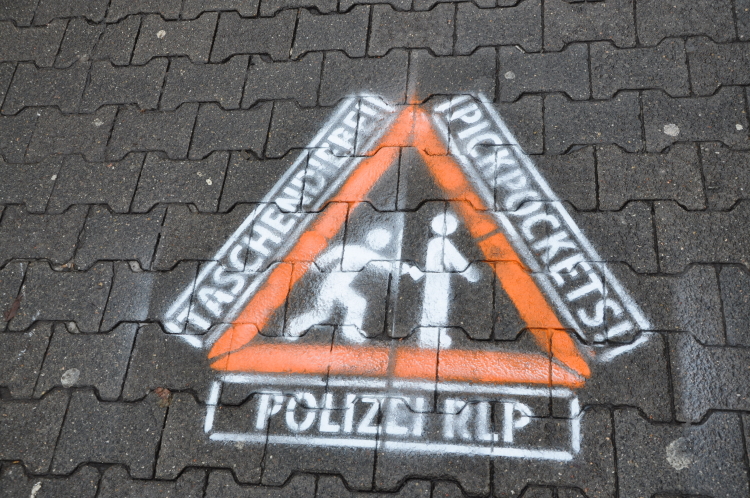 Eines der aufgesprühten Warnhinweise in Form eines dreieckigen Verkehrsschildes mit roter Umrandung. © Polizeipräsidium Westpfalz