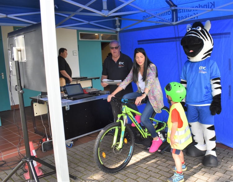 Unter den wachsamen, wenn auch nicht immer fokussierten Augen von KUK-Maskottchen Sam probierte Anja Pfeiffer den Fahrradsimulator direkt selbst aus. Tipps gab es vom jungen Fahrradnachwuchs. © Stadt Kaiserslautern