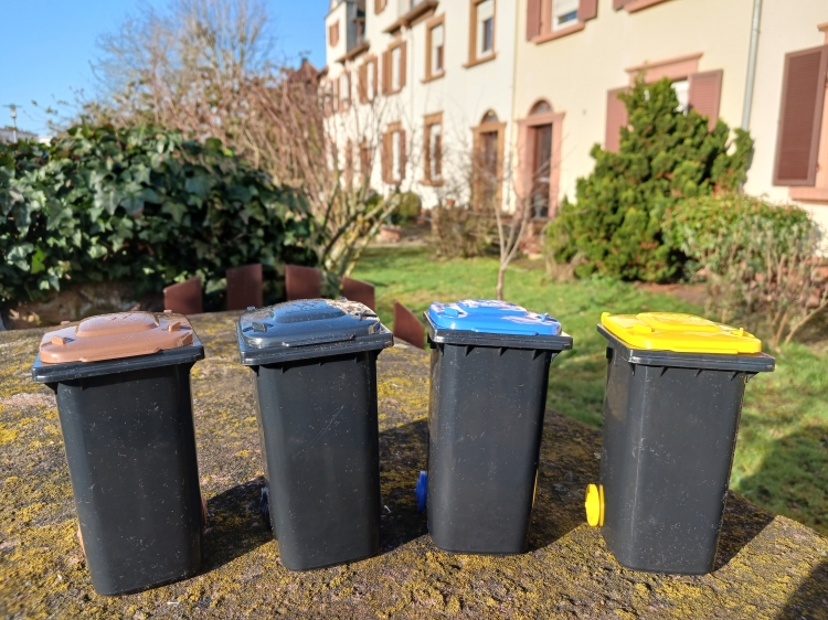 Vier Mini-Spielzeug-Mülltonnen stehen vor einem Gebäude. © Stadtbildpflege Kaiserslautern