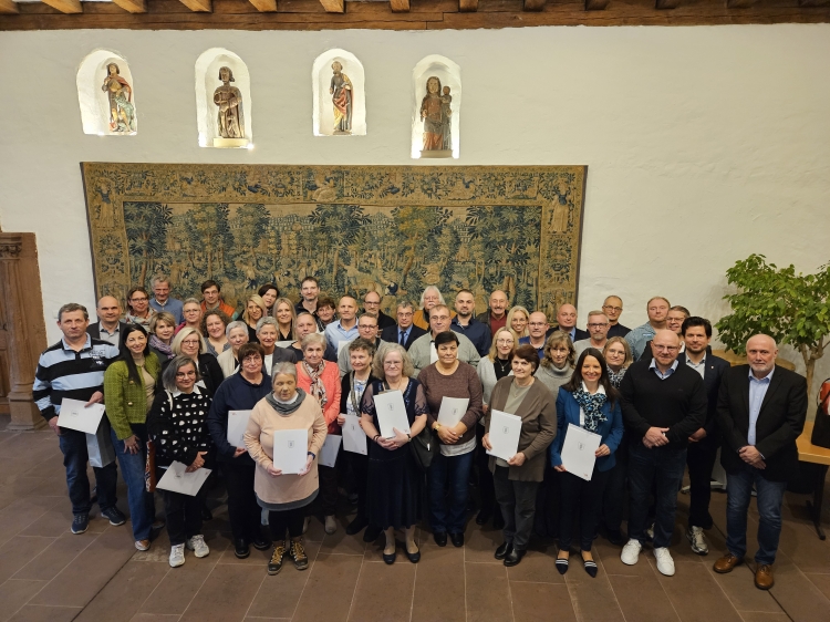 Die Jubilarinnen und Jubilare stehen gemeinsam mit dem Stadtvorstand und ihren Referatsleitungen vor dem Wandteppich im Pfalzgrafensaal. © Stadt Kaiserslautern