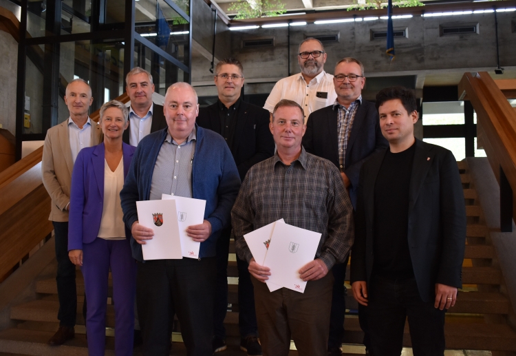 Die beiden Jubilare stehen mit Beate Kimmel und Manuel Steinbrenner und den weiteren Gratulanten auf der Treppe im Rathausfoyer. © Stadt Kaiserslautern