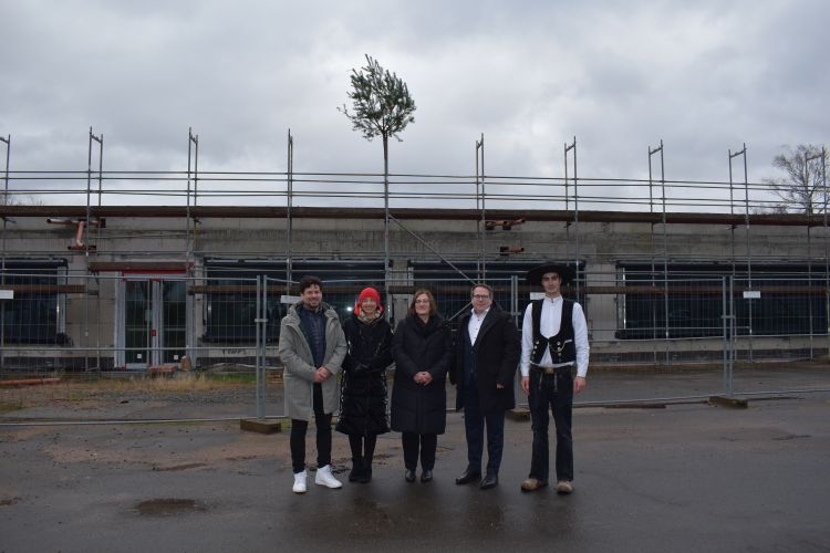 Baudezernent Manuel Steinbrenner mit Schuldezernentin Anja Pfeiffer, Schulleiterin Günther, ADD-Präsident Linnertz und Lucas Marx, der den Richtspruch vornahm. Im Hintergrund das Schulgebäude, auf dessen Dach der Richtstrauß angebracht ist. © Stadt Kaiserslautern