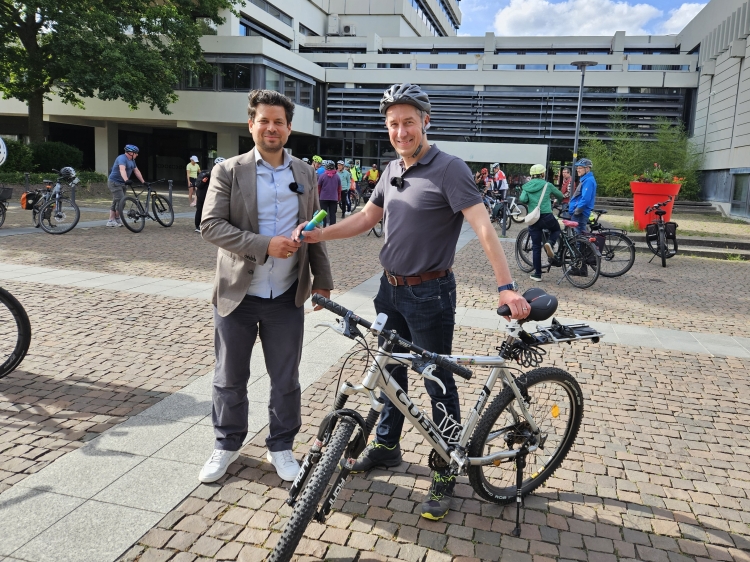 Beigeordneter Manuel Steinbrenner übergibt den Staffelstab des Stadtradelns 2026 an den Ersten Kreisbeigeordneten Jan Schneider. © Stadt Kaiserslautern