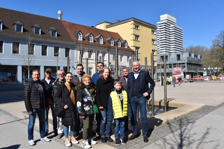 Das Gruppenfoto zeigt Peter Kiefer mit Mitarbeiterinnen und Mitarbeitern des Referats Gebäudewirtschaft (samt Nachwuchs) sowie der Vorsitzenden des Seniorenbeirats, Helga Bäcker, vor dem Leo-Erb-Brunnen mit Blick Richtung Rathaus. © Stadt Kaiserslautern