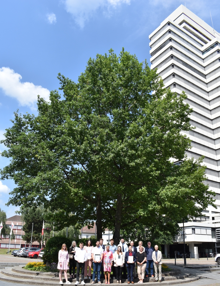 Die im Text genannten Personen stehen vor dem Baum auf dem Rathausvorplatz, das Rathaus im Hintergrund. © Stadt Kaiserslautern