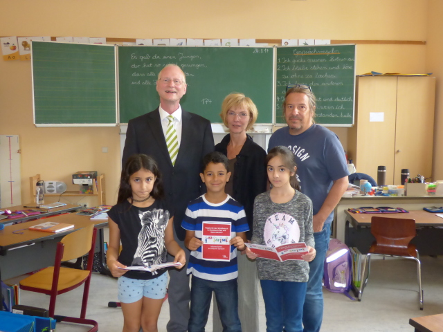 Beigeordneter Joachim Färber und Sabine Michels vom Projektbüro für Integration und Interkulturelle Angelegenheiten präsentieren mit drei Kindern der Röhmschule die neue Broschüre über das deutsche Schulsystem. Hinten rechts Schulleiter Reiner Kiebel.  © Stadt Kaiserslautern