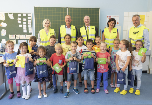 Schüler der 1. Klasse mit ihren Geschenken und im Hintergrund stehend von links nach rechts: Simone Arnold, Rektorin der Geschwister-Scholl-Grundschule, Richard Mastenbroek, Vorstandsmitglied der SWK, Joachim Färber, Beigeordneter der Stadt Kaiserslautern, Bettina Bastian, Abteilungsleiterin Vertrieb der SWK, Markus Vollmer, Vorstandsmitglied der SWK © SWK