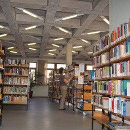 Links und rechts stehen Bücherregale gefüllt mit Büchern unterschiedlicher Farbe und Größe. Alle tragen einen Aufkleber, damit sie schneller gefunden werden können.