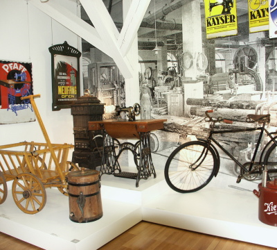 Ausgestellt werden eine Pfaff-Nähmaschine, ein Neufang-Ofen, ein Fahrrad, ein Bollerwagen, ein Topf von Kieffer.