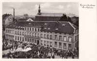 Eine Fotografie, die das alte Gebäude des Museums zeigt. Der Stiftsplatz vor dem Gebäude ist stark belebt, u.a. wegen den aufgebauten Marktständen.