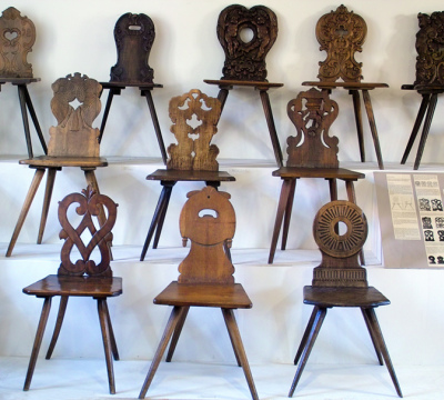 Eine große Anzahl an Holzstühlen mit kunstvoll geschnitzten Rückenlehnen. 