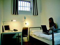 In proper style, the visitor carries black and white striped clothing. With a laptop on her lap she is sitting on the bed.