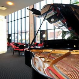 An unfolded grand piano in the lounge of the Pfalztheatre. A large window front on which some seating available with tables, offers plenty of light.