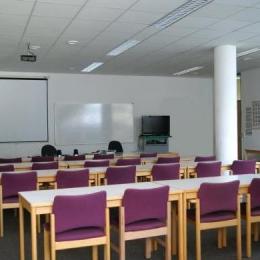 A smaller meeting room with flat screen TV, whiteboard and projector.