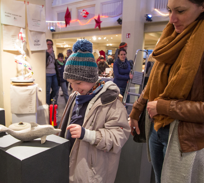 kleiner Junge mit seiner Mutter vor einer Porzellanfigur